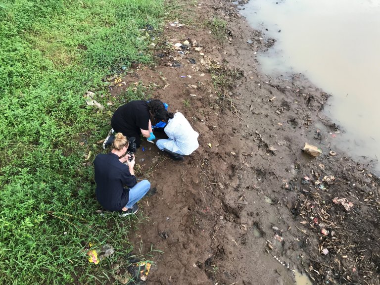 People by river bed taking samples.