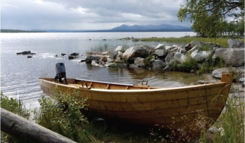 Bilde av liten trebåt trukket halvveis på land. 