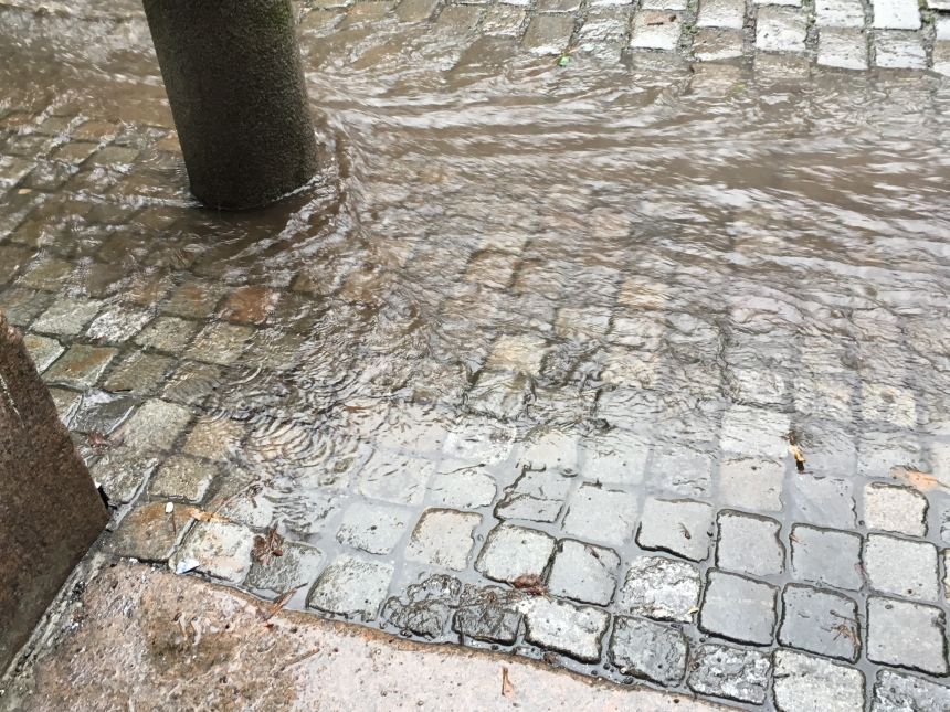 Bilde av rennende vann over brostein. 