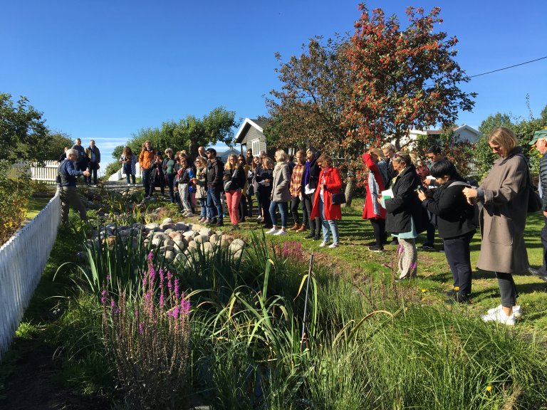 Man lecturing, people listening, in green garden