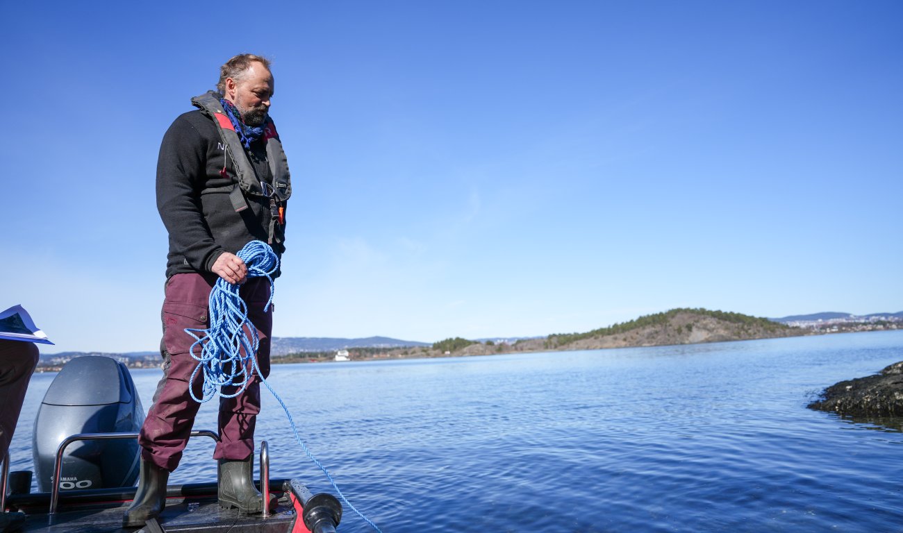 Mann i båt ser utover vann 