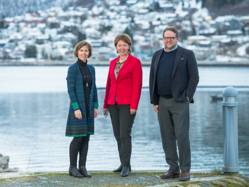 To kvinner og en mann foran vann i vinterlige omgivelser. 